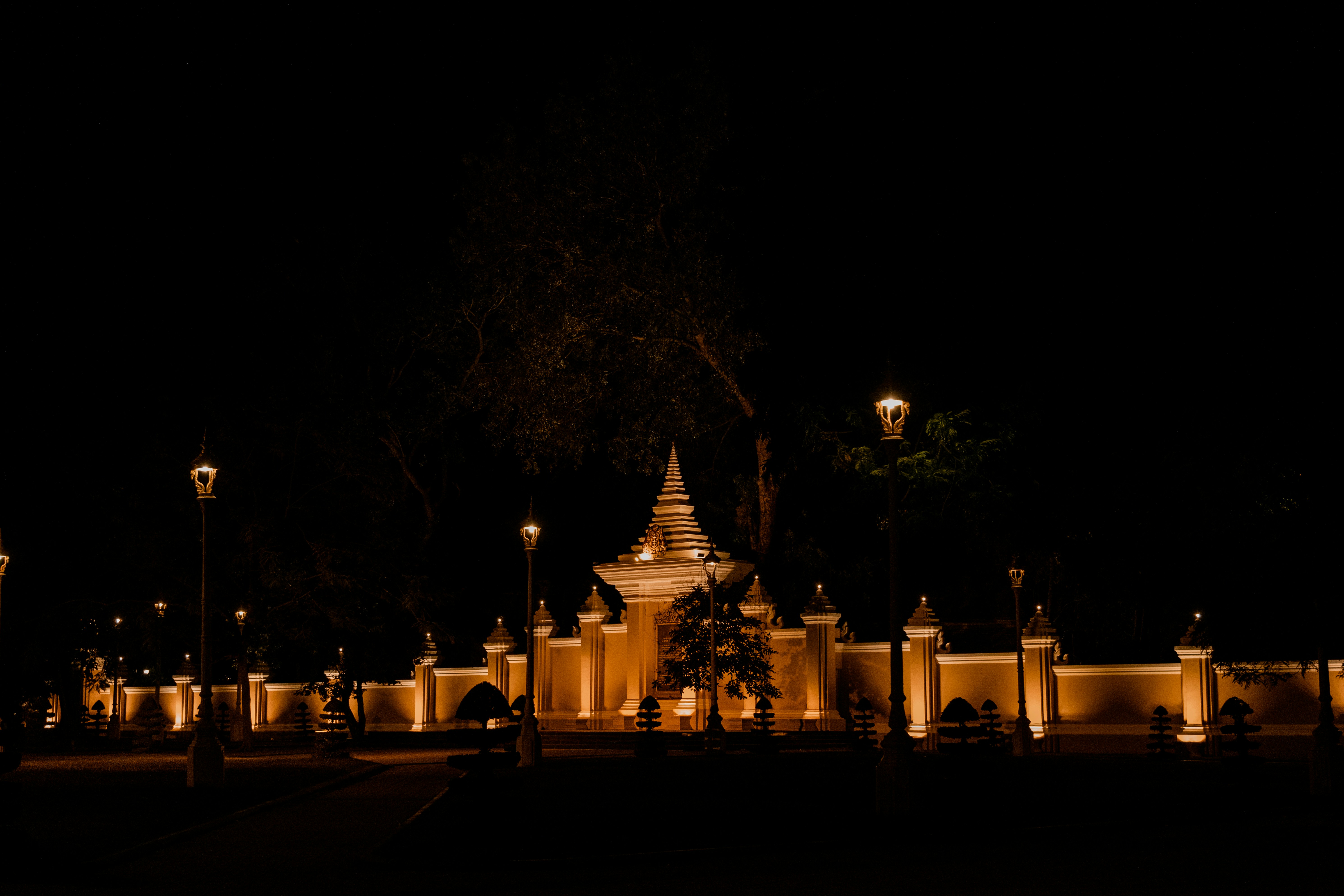 The Royal Palace of Cambodia illuminated at night, its golden roofs glowing against the dark Phnom Penh skyline.